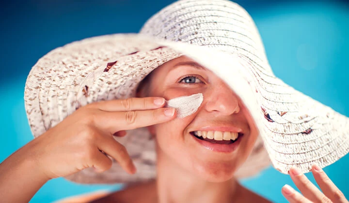 Frau trägt Sonnencreme im Gesicht auf Frau trägt Sonnencreme im Gesicht auf
